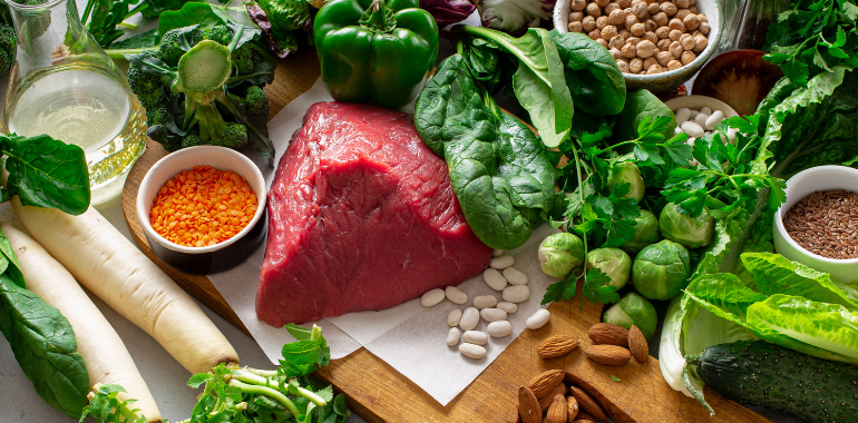 slab of meet raw vegetables on cutting board nuts brussel sprouts lentils cabbage